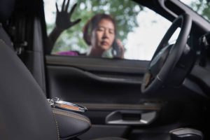 A woman stands outside a car window, making a phone call while looking at a set of keys on the front seat inside the vehicle. Emergency Locksmith in East Danforth Emergency Locksmith in Eglinton West Emergency Car Lockout