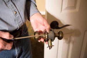 Person installing a brass doorknob with a screwdriver on a white door. Emergency Locksmith in Bridle Path Emergency Locksmith in North Toronto Emergency Locksmith in Oakridge Emergency Locksmith in Rockcliffe-Smythe Front Door Lock Change In Toronto Locksmith in Bedford Park